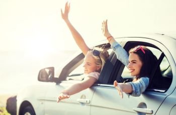 summer vacation, holidays, travel, road trip and people concept - happy teenage girls or young women in car at seaside waving hands. happy teenage girls or women in car at seaside