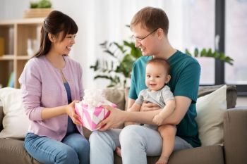 family, parenthood and mothers day concept - happy mother receiving gift box from father and baby boy at home. happy family with gift and baby boy at home
