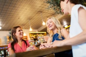 people, celebration and lifestyle concept - happy women drinking wine and talking at bar or restaurant. happy women drinking wine at bar or restaurant