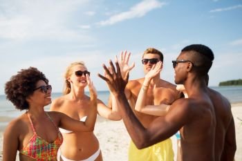 friendship, summer holidays and people concept - group of happy friends making high five on beach. happy friends making high five on summer beach