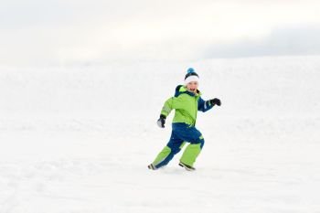 childhood, leisure and season concept - happy boy having fun outdoors in winter. happy boy having fun outdoors in winter