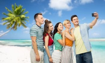 travel, technology and summer holidays concept - group of happy smiling friends taking selfie by smartphone over tropical beach background in french polynesia. friends taking selfie by smartphone over beach
