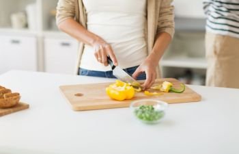 food, cooking and culinary concept - close up of woman chopping vegetables at home. close up of woman chopping vegetables at home