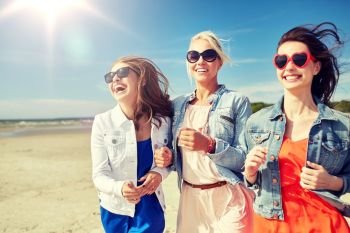 summer vacation, holidays, travel and people concept - group of smiling young women in sunglasses and casual clothes running along beach. group of smiling women in sunglasses on beach