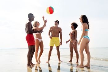 friendship, summer holidays and people concept - happy friends playing with inflatable ball on beach. friends playing with beach ball in summer