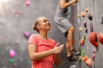 fitness, extreme sport and healthy lifestyle concept - young man and woman bouldering on a rock climbing wall at indoor gym. man and woman climbing a wall at indoor gym