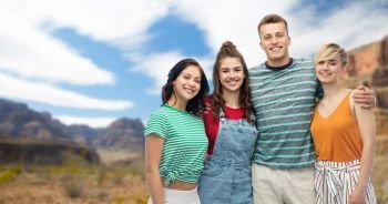 travel, tourism and summer holidays concept - group of happy smiling friends hugging over grand canyon national park background. happy friends hugging over grand canyon