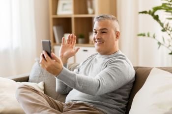 technology, people and communication concept - happy man having video chat on smartphone at home. man having video chat on smartphone at home