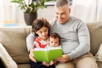 family, fatherhood and people concept - happy father with preteen and baby son reading book at home. happy father with sons reading book at home