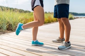 fitness, sport and footwear concept - legs of couple of sportsmen in sneakers outdoors. legs of couple of sportsmen in sneakers outdoors