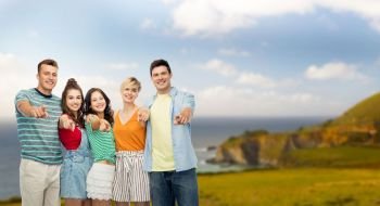 travel, tourism and summer holidays concept - group of happy smiling friends hugging pointing at you over big sur coast of california background. happy friends hugging and pointing at you