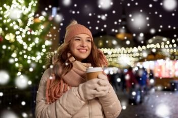winter holidays, hot drinks and people concept - happy young woman with coffee at christmas market in evening. happy young woman with coffee at christmas market