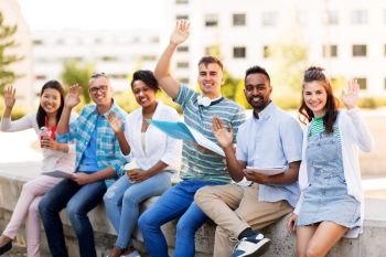 education, international and people concept - group of happy exchange students with notebook and takeaway drinks waving hands outdoors. students with notebook waving hands outdoors