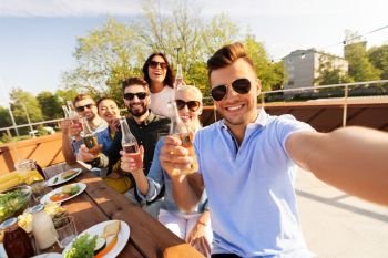leisure and people concept - happy friends having bbq party on rooftop in summer and taking selfie. happy friends taking selfie at rooftop party