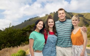 travel, tourism and summer holidays concept - group of happy smiling friends hugging over big sur hills and road background in california. happy friends hugging over big sur hills and road