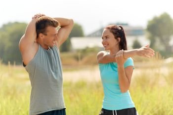 fitness, sport, training and lifestyle concept - smiling couple stretching outdoors. smiling couple stretching outdoors