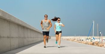 fitness, sport and lifestyle concept - happy couple in sports clothes and sunglasses running outdoors. couple in sports clothes running outdoors