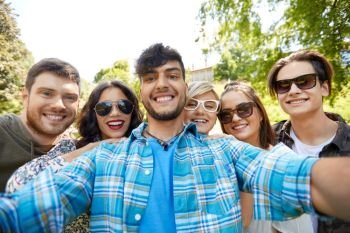 friendship, leisure and technology concept - group of happy smiling friends taking selfie at summer park. happy smiling friends taking selfie at summer park