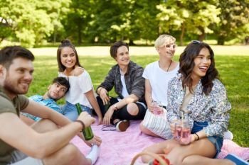 friendship and leisure concept - group of happy friends with non alcoholic drinks at picnic in summer park. happy friends with drinks at picnic in summer park
