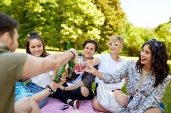 leisure, people and celebration concept - happy friends clinking non alcoholic drinks at picnic in summer park. happy friends clinking drinks at summer park