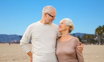 old age, travel and tourism concept - happy senior couple hugging over venice beach background in california. happy senior couple hugging over venice beach