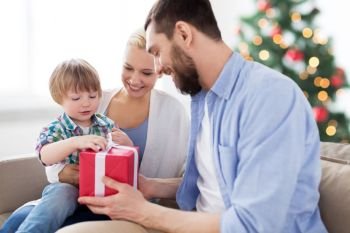 people and holidays concept - happy family with birthday gift at home over christmas tree lights background. happy family with christmas gift at home