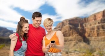 travel, tourism and technology concept - group of happy smiling friends with smartphone over grand canyon national park background. friends with smartphone over grand canyon
