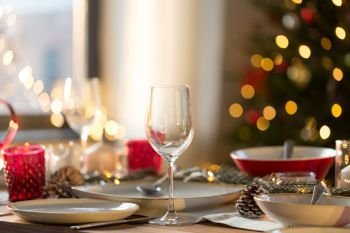 christmas, holidays and table setting concept - wine glass and tableware for festive dinner at home. table setting for christmas dinner at home