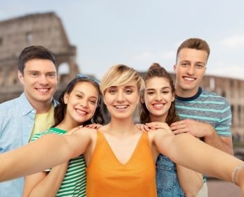 travel, tourism and vacation concept - group of happy smiling friends taking selfie over coliseum background. happy friends taking selfie over coliseum