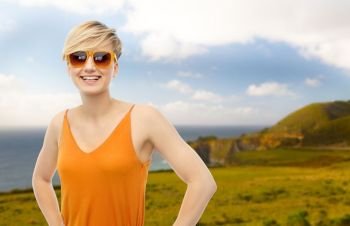 travel, tourism and summer holidays concept - happy smiling teenage girl in sunglasses over big sur coast of california background. happy smiling teenage girl over background