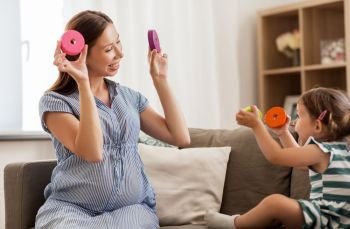 childhood and people concept - happy pregnant mother and little daughter playing with toy blocks at home. pregnant mother and daughter with toy blocks