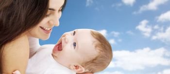 family and motherhood concept - happy smiling young mother with little baby over sky background. mother with baby over sky background