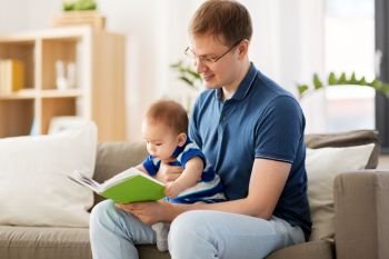 family, fatherhood and people concept - happy father and little baby son with book at home. happy father and little baby son with book at home