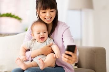family and motherhood concept - happy smiling young asian mother with little baby son taking selfie by smartphone at home. asian mother with baby son taking selfie at home