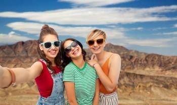 travel, tourism and vacation concept - group of happy female smiling friends in sunglasses taking selfie over grand canyon national park background. female friends taking selfie over grand canyon