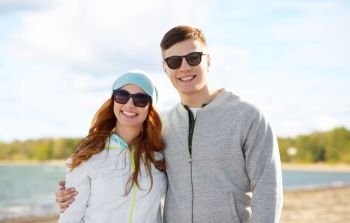 people and leisure concept - happy teenage couple over beach background. happy teenage couple over beach background