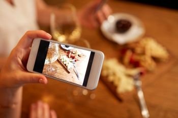 people, technology and lifestyle concept - hand picturing food by smartphone at wine bar. hand picturing food by smartphone at wine bar