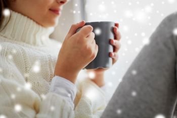 hot drinks and people concept - close up of girl in winter sweater with cacao mug sitting at home window. close up of girl in winter sweater with cacao mug