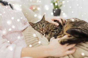 pets, hygge and winter concept - close up of female owner with tabby cat in bed at home over snow. close up of owner with tabby cat in bed over snow