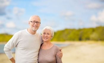 old age, retirement and people concept - happy senior couple hugging over beach background. happy senior couple hugging over beach background