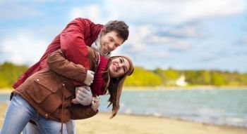 love, relationships and people concept - happy teenage couple having fun over autumn beach background. happy couple having fun over autumn beach