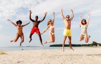 friendship, summer holidays and people concept - group of happy friends jumping and having fun on beach. happy friends jumping on summer beach
