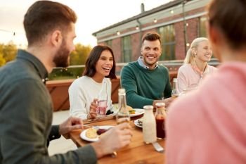 leisure and people concept - happy friends having dinner or rooftop party in summer. friends having dinner or rooftop party in summer