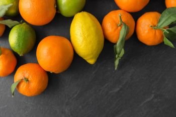 food, healthy eating and vegetarian concept - close up of citrus fruits on stone table. close up of citrus fruits on stone table