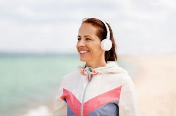 music, technology and people concept - smiling woman with headphones on beach. smiling woman with headphones on beach