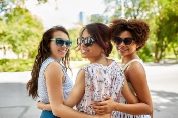 female friendship, people and leisure - happy young women in sunglasses at summer park. happy young women in sunglasses at summer park