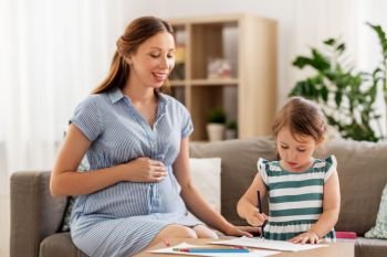 pregnancy, people and family concept - happy pregnant mother and little daughter drawing at home. pregnant mother and daughter drawing at home