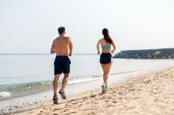 fitness, sport and lifestyle concept - happy couple running along summer beach. couple in sports clothes running along on beach