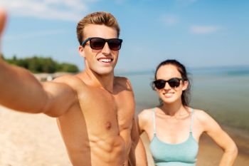 fitness, sport and lifestyle concept - happy couple taking selfie on summer beach. couple taking selfie on summer beach