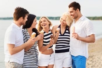 friendship, leisure and people concept - group of happy friends in striped clothes eating ice cream on beach. happy friends eating ice cream on beach